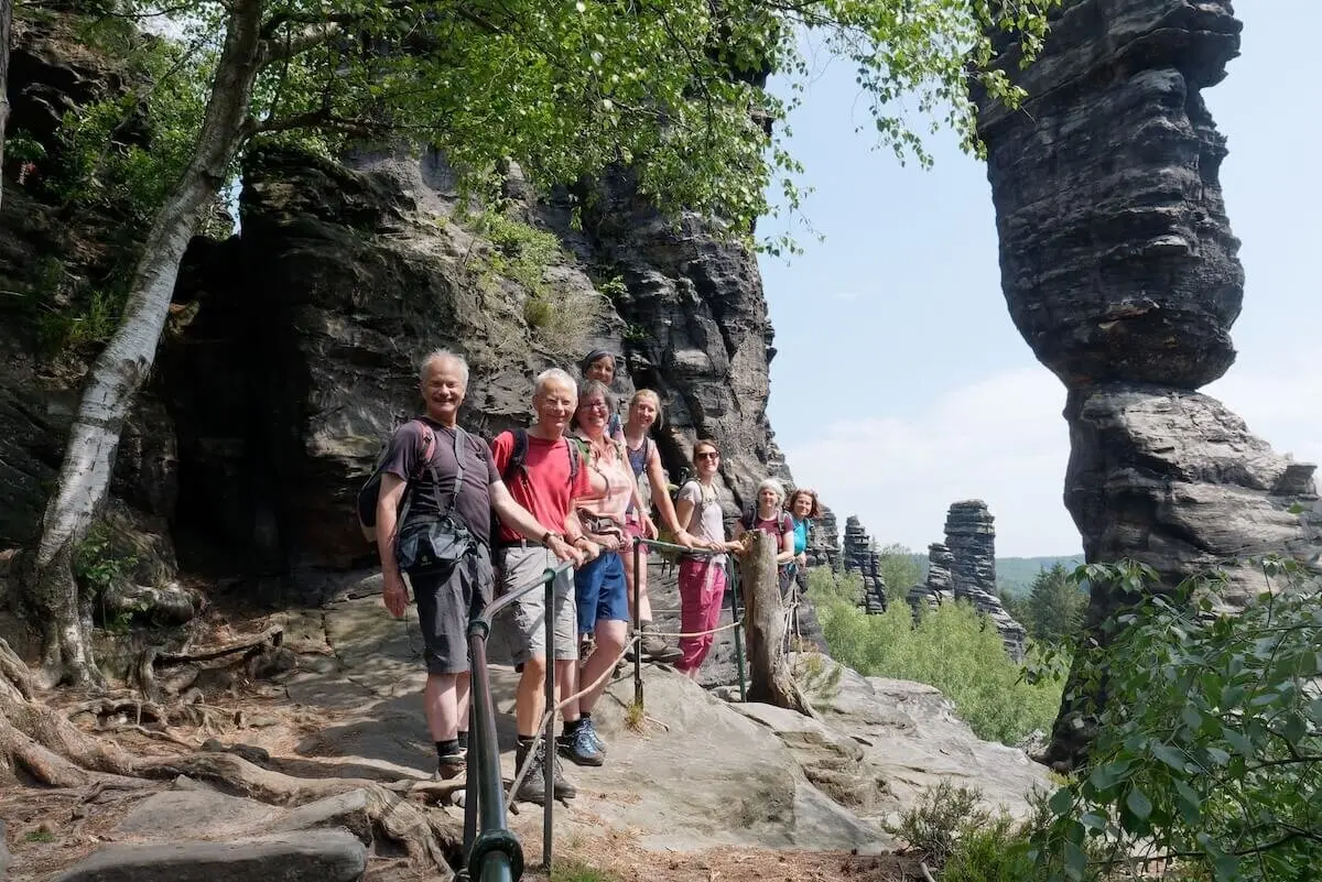 Wandergruppe steht auf Felsweg mit Geländer; markante Felsformationen und Bäume im Hintergrund. | © DAV Markt Schwaben/Lutz Gründel