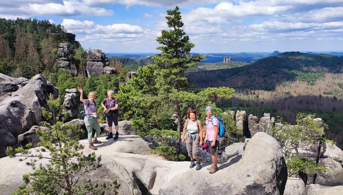 Fünf Wandernde stehen auf Felsplateau mit Blick auf bewaldete Hügel und Felsformationen unter wolkigem Himmel. | © DAV Markt Schwaben | Foto Josephine Freikamp