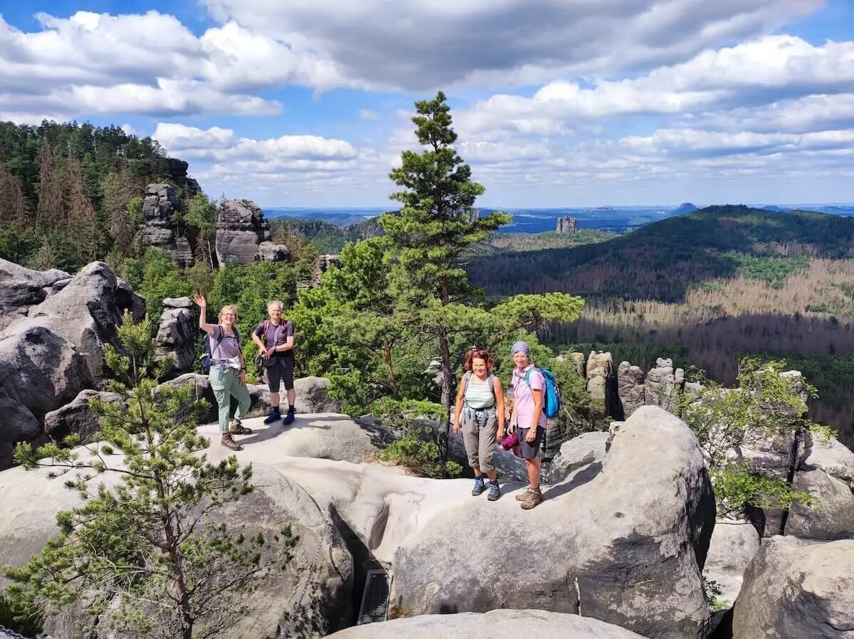 Fünf Wandernde stehen auf Felsplateau mit Blick auf bewaldete Hügel und Felsformationen unter wolkigem Himmel. | © DAV Markt Schwaben | Foto Josephine Freikamp
