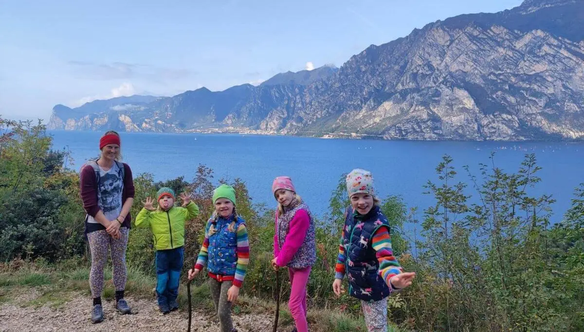 Mehrere Kinder und eine erwachsene Person stehen an einem Aussichtspunkt über dem Gardasee, dahinter erheben sich steile Berge. | © DAV Markt Schwaben / Silke Titze