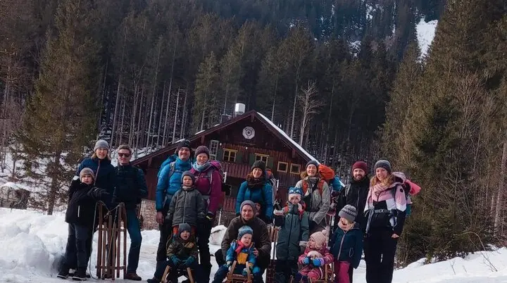 Gruppe aus Kindern und Erwachsenen posiert fröhlich vor dem Blecksteinhaus am Spitzingsee in winterlicher Schneelandschaft. | © DAV Markt Schwaben