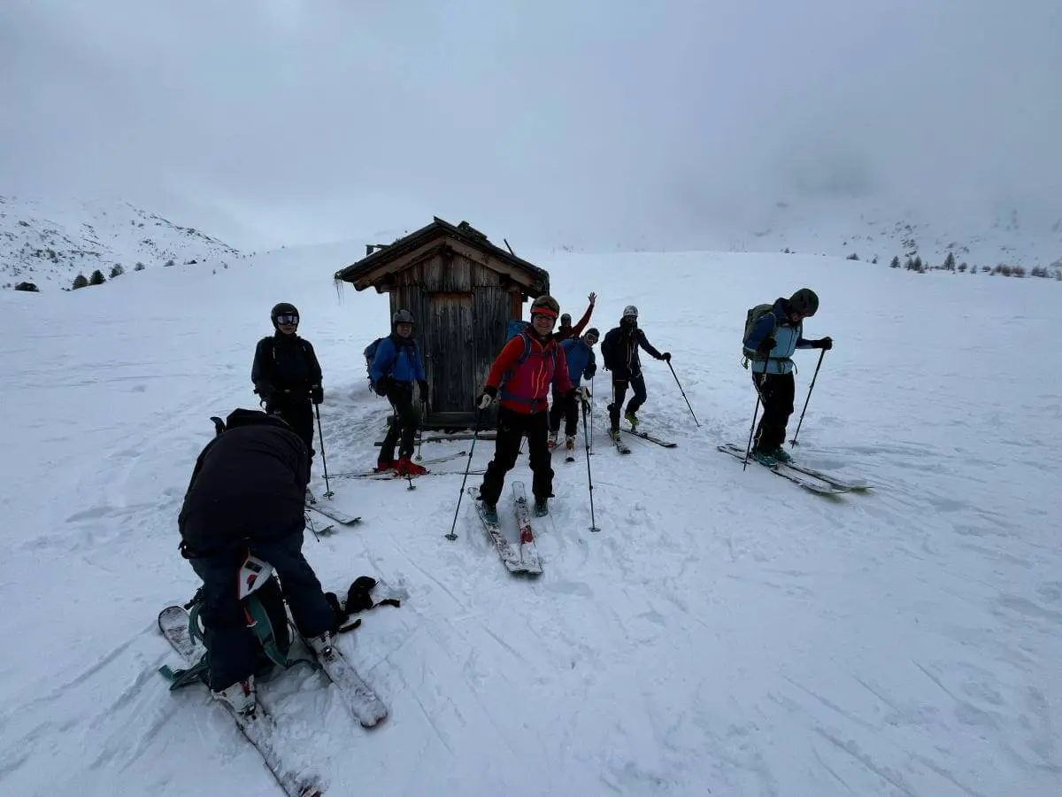 Skitourengruppe bereitet sich vor der kleinen Holzhütte auf die Abfahrt vor; eine Person beim Abfellen im Vordergrund. | © DAV Markt Schwaben · Foto: Markus Sellmeier