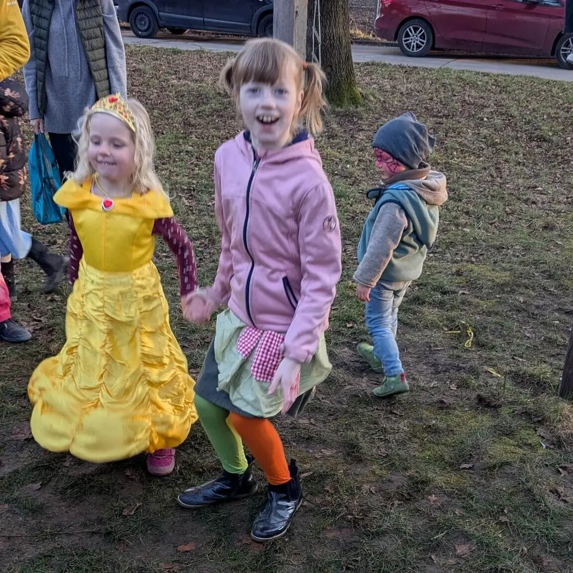 Drei lächelnde Kinder in bunten und verspielten Outfits draußen auf einer Wiese. | © DAV Markt Schwaben