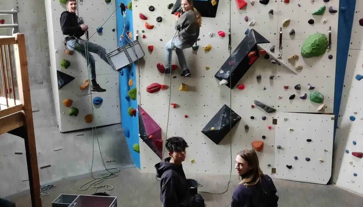 Vier Personen in einer Indoor-Kletterhalle, zwei klettern gesichert, zwei beobachten mit Kletterausrüstung | © DAV Markt Schwaben
