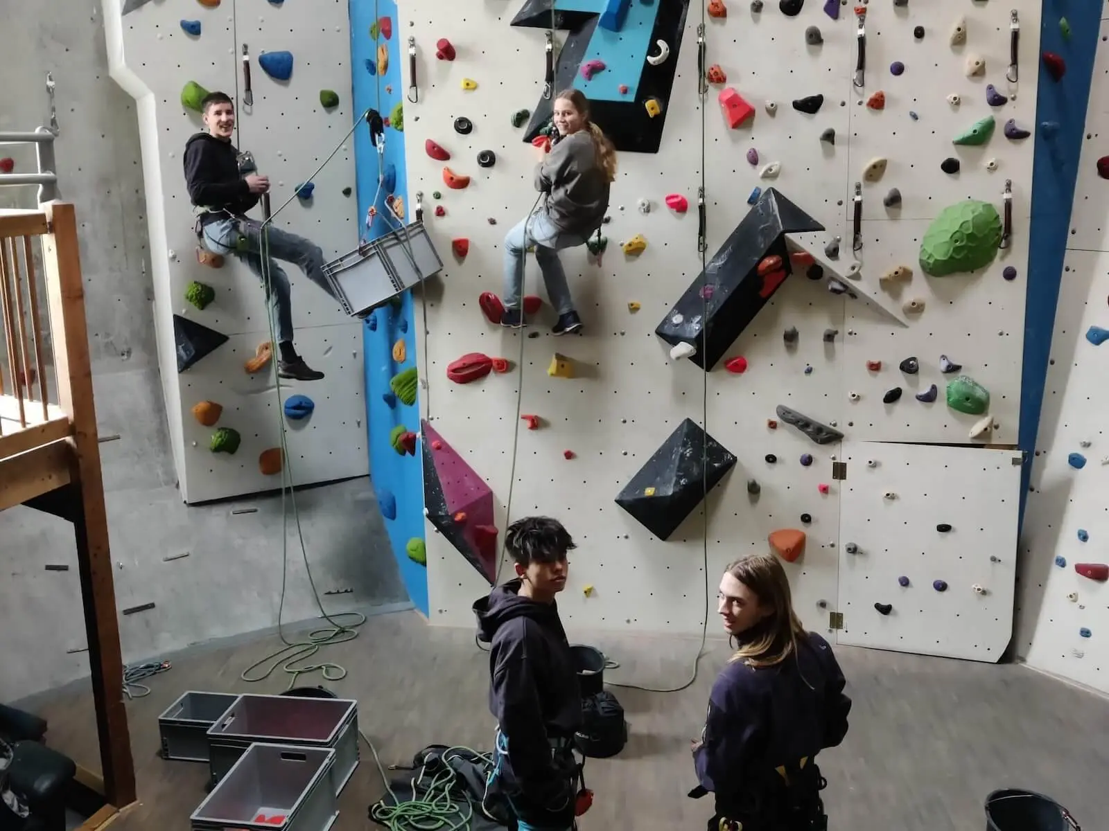 Vier Personen in einer Indoor-Kletterhalle, zwei klettern gesichert, zwei beobachten mit Kletterausrüstung | © DAV Markt Schwaben