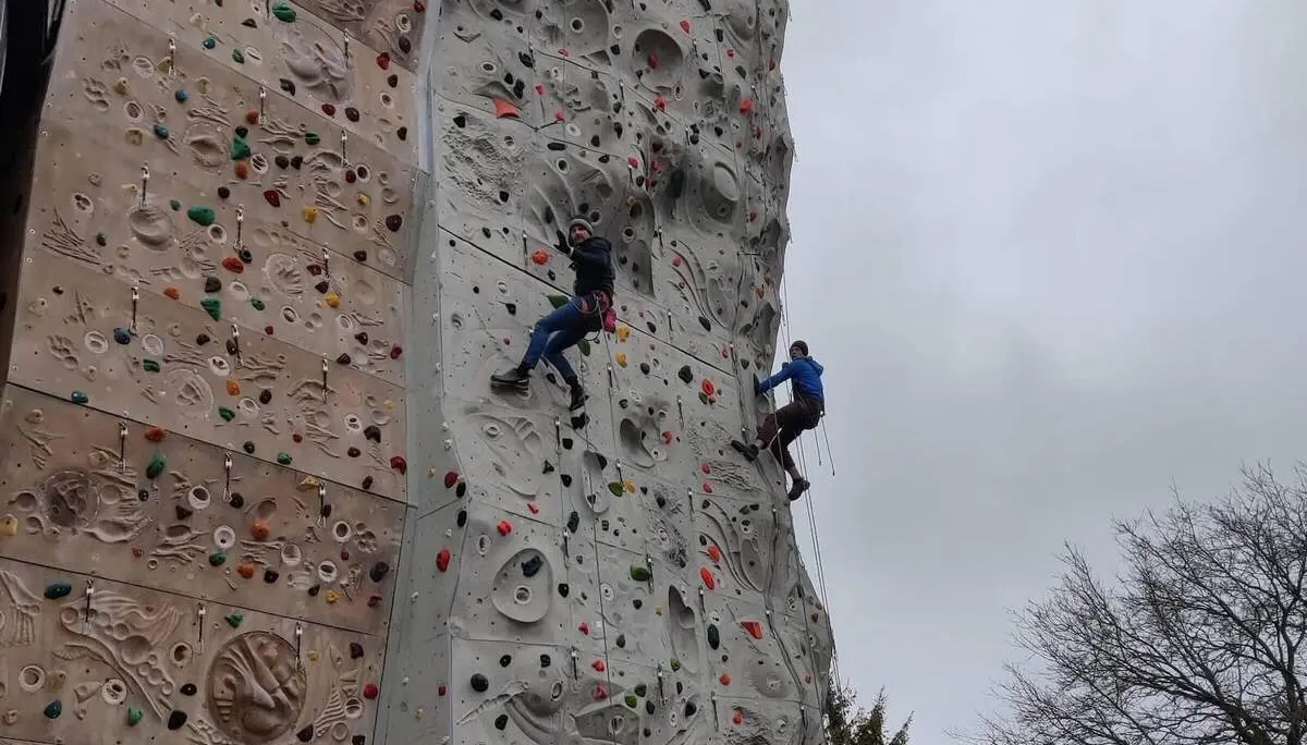 Zwei Personen klettern an einer großen Outdoor-Kletterwand mit bunten Griffen. | © DAV Markt Schwaben