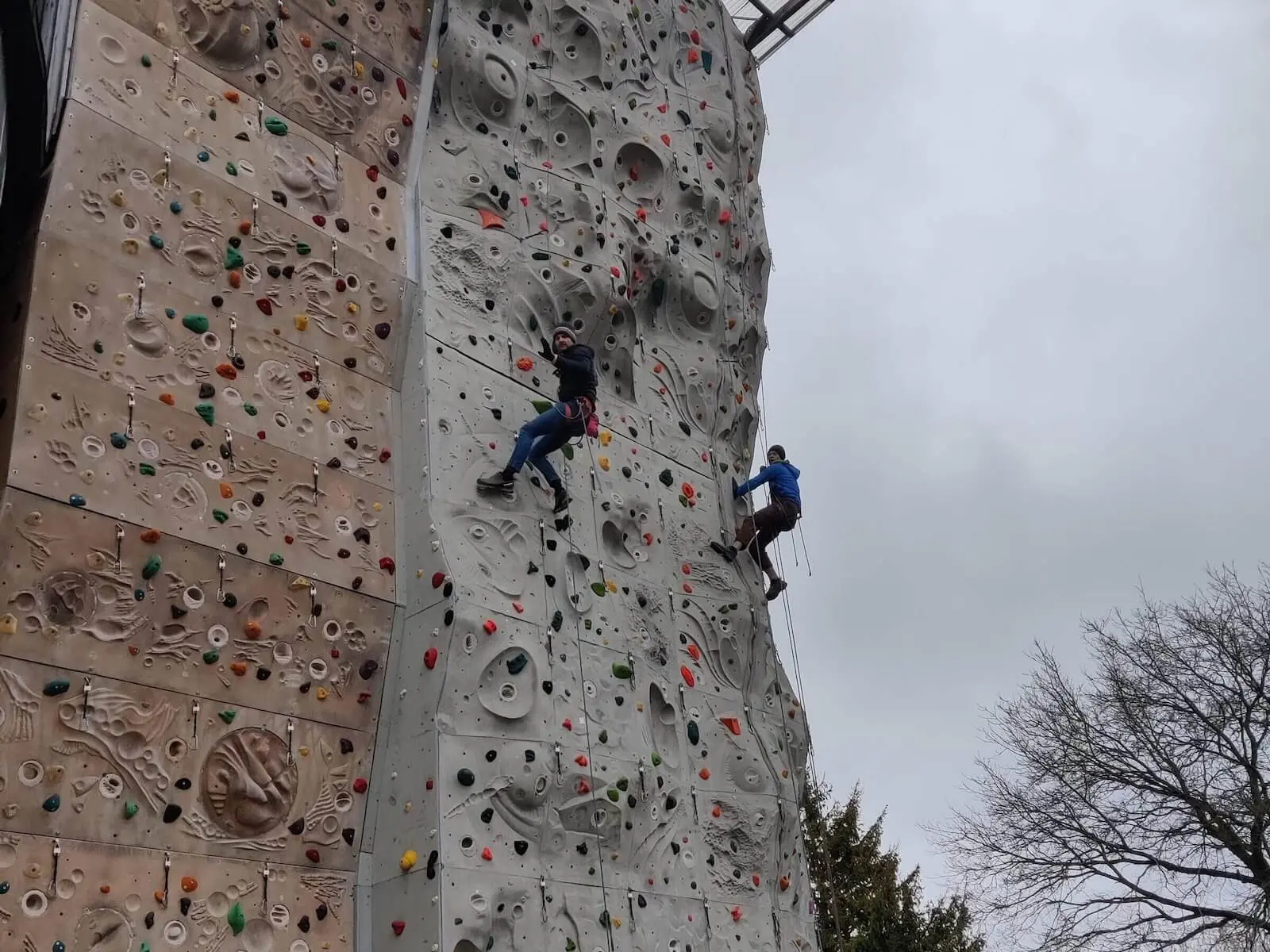 Zwei Personen klettern an einer großen Outdoor-Kletterwand mit bunten Griffen. | © DAV Markt Schwaben