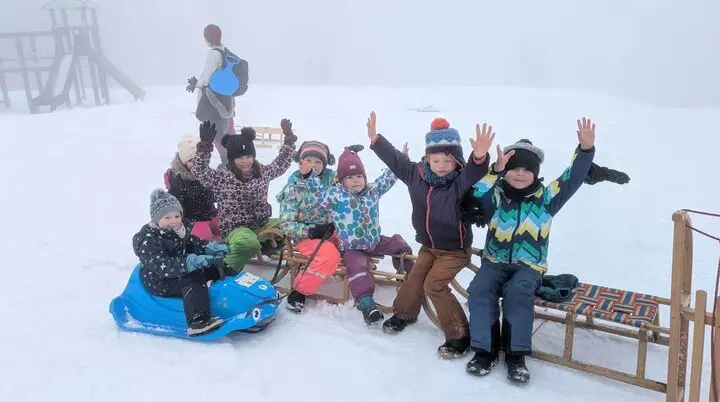 Kinder genießen das Winterrodeln mit Schlitten in einem schneebedeckten, nebligen Gelände. | © DAV Markt Schwaben
