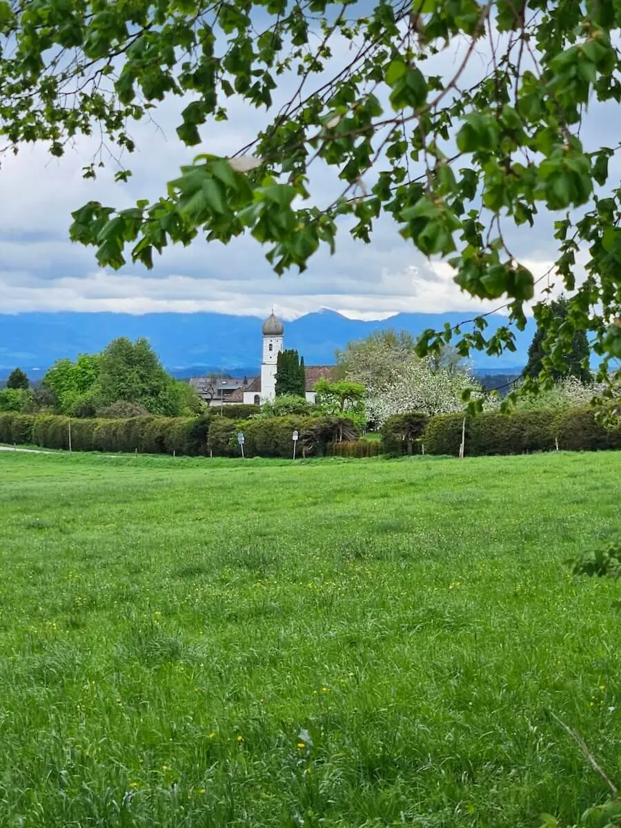 Dorfansicht mit Kirche und Alpenpanorama. | © DAV Markt Schwaben / Hubert Inhofer