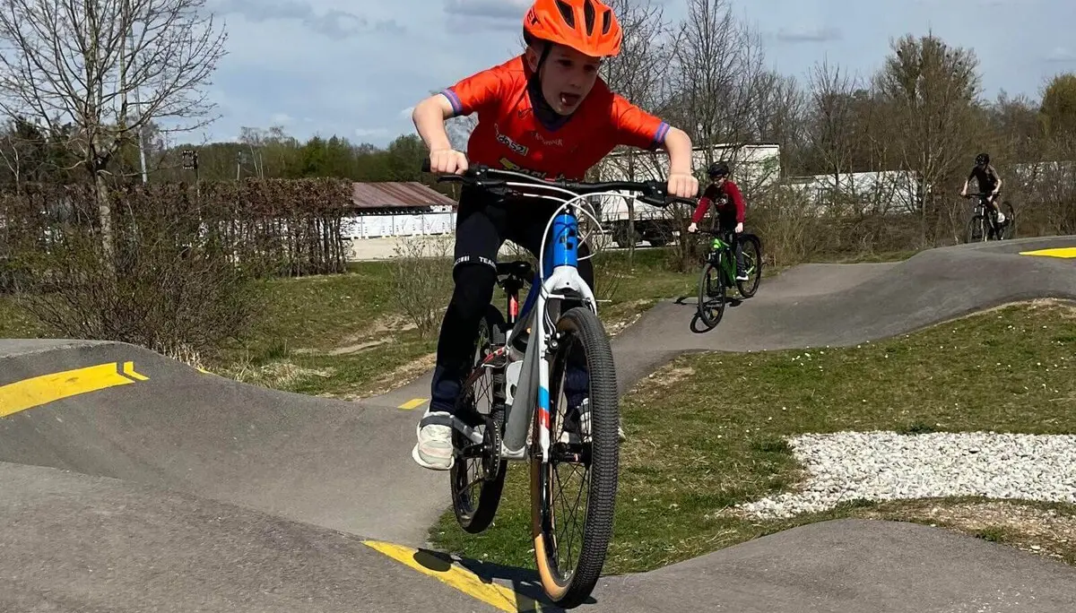 Person in orangem Helm und Shirt springt mit Fahrrad über BMX-Rampe – Action und Techniktraining pur! | © DAV Markt Schwaben | Foto Miron Thoms