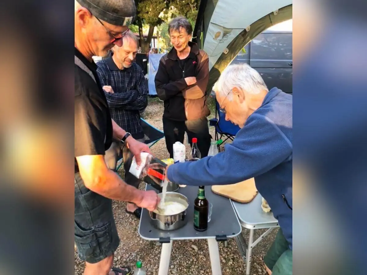 Vier Personen bereiten gemeinsam Essen am Campingtisch zu; Gewürze und Kochutensilien gut sichtbar. | © DAV Markt Schwaben | Foto Hildegard Petschik