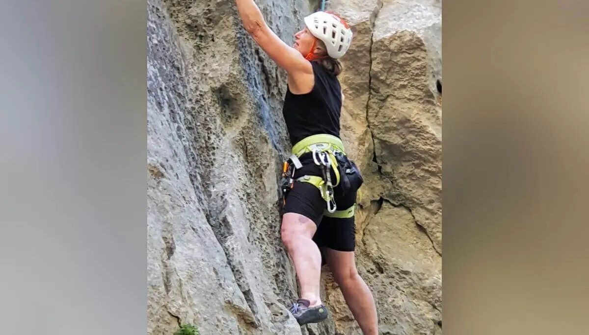 Eine Person mit Helm und Klettergurt steigt konzentriert an rauer Felswand mit kleinen Pflanzen empor. | © DAV Markt Schwaben | Foto Karin und Peter Tkaczuk