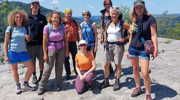Neun Personen posieren auf Felsplateau mit Blick auf Hügel und Wald, Himmel leicht bewölkt. | © DAV Markt Schwaben | Foto Lutz Gründel