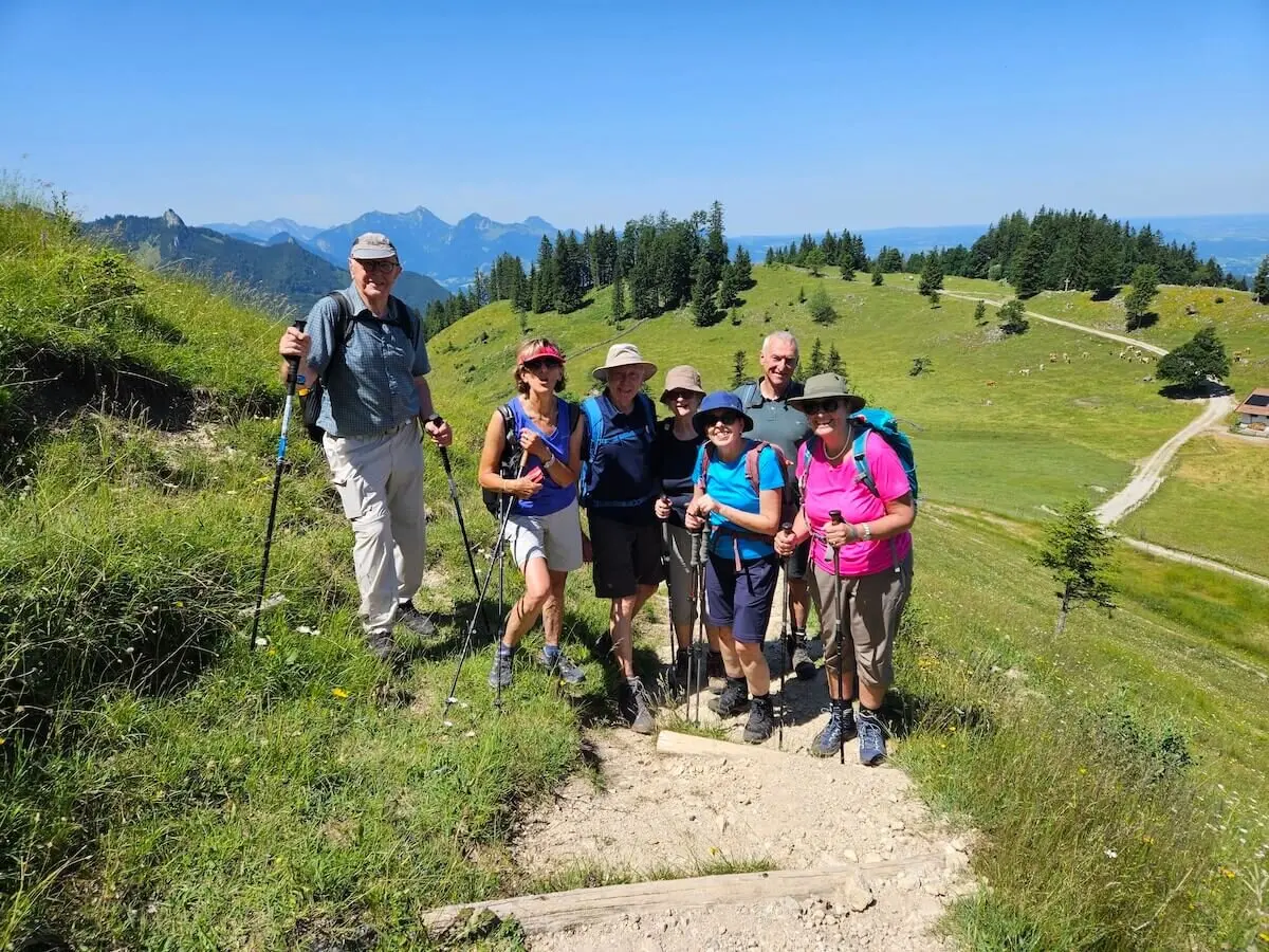 Sieben ältere Wanderer stehen mit Ausrüstung auf einem Pfad in alpiner Landschaft mit weitem Blick über Hügel und Täler. | © DAV Markt Schwaben | Foto Hubert Inhofer