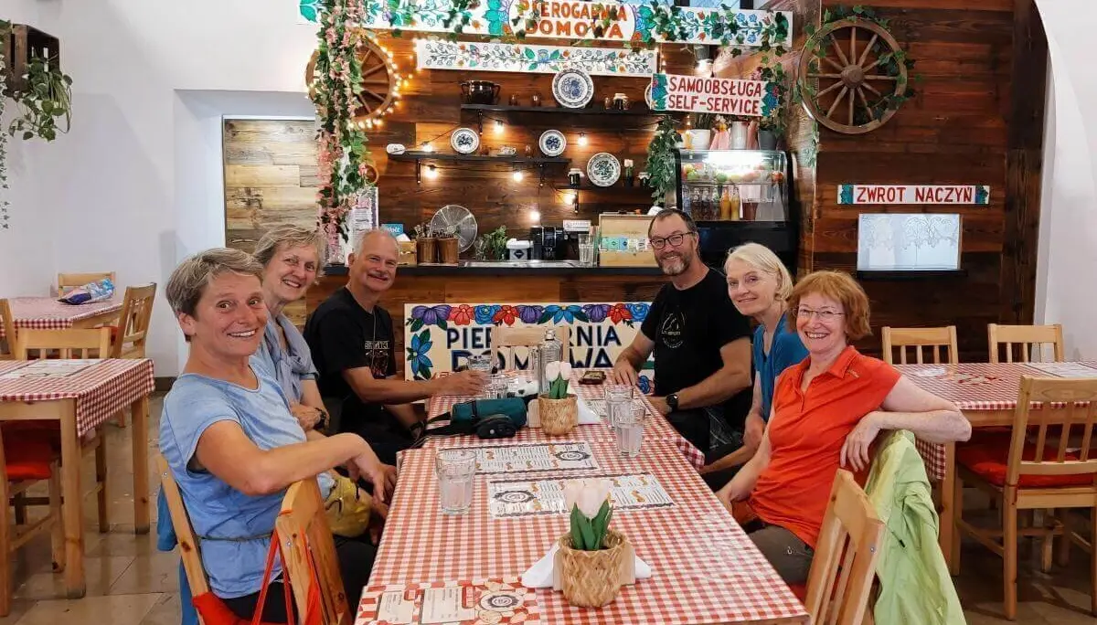 Sechs Personen sitzen an gedecktem Tisch in gemütlichem Lokal mit rot-weißem Dekor; im Hintergrund Theke mit polnischer Beschriftung. | © DAV Markt Schwaben | Foto Michaela Haaß