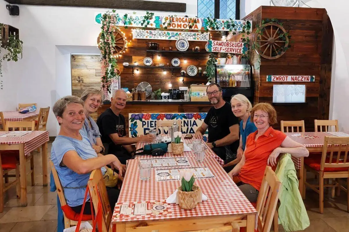 Sechs Personen sitzen an gedecktem Tisch in gemütlichem Lokal mit rot-weißem Dekor; im Hintergrund Theke mit polnischer Beschriftung. | © DAV Markt Schwaben | Foto Michaela Haaß