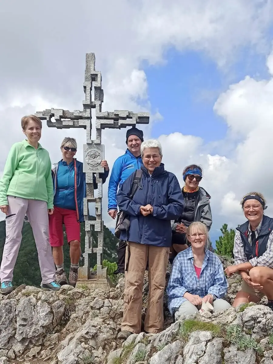 Sieben Erwachsene posieren am Gipfelkreuz der Hördlwand. | © DAV Markt Schwaben