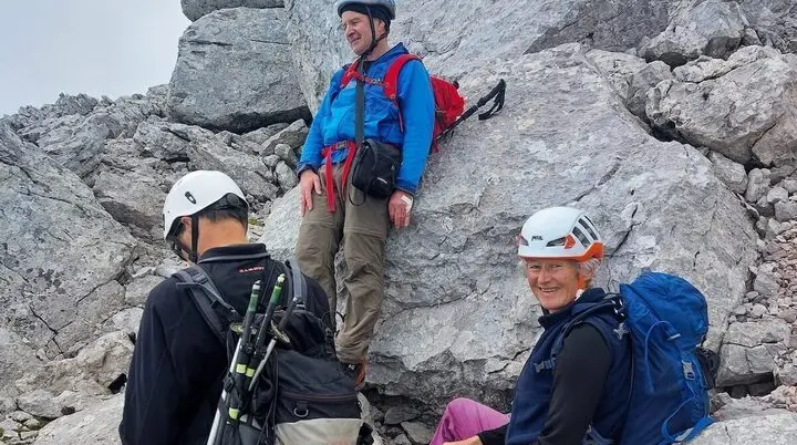 Drei Bergsteiger rasten auf felsigem Grat, einer sitzt lächelnd, hinten steiles Gelände und Waldhang. | © DAV Markt Schwaben · Foto: Lutz Gründel