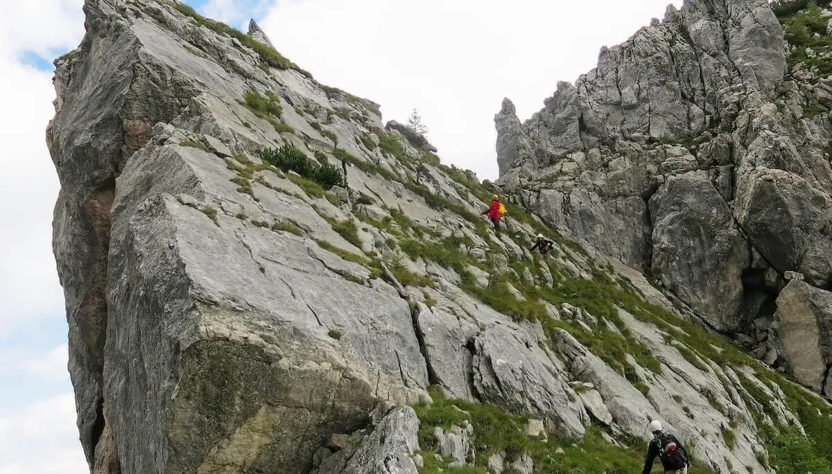 Mehrere Bergsteiger steigen über steile Felsplatten mit Grasinseln, Gelände wirkt rau und alpin. | © DAV Markt Schwaben · Foto: Erwin Matzinger