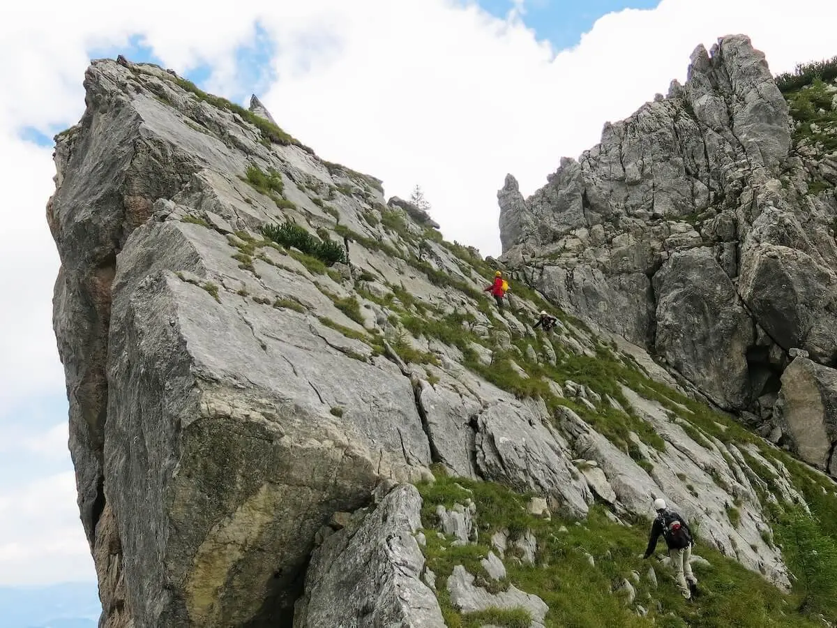 Mehrere Bergsteiger steigen über steile Felsplatten mit Grasinseln, Gelände wirkt rau und alpin. | © DAV Markt Schwaben · Foto: Erwin Matzinger