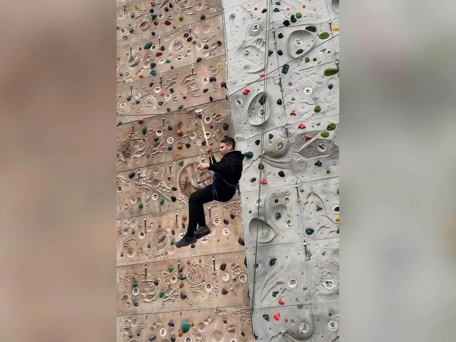 Ein Jugendlicher der Jugendgruppe hängt gesichert an einem Seil vor einer Indoor‑Kletterwand und führt eine Schaukelbewegung aus. | © DAV Mark Schwaben / Wiebke Rauschenbach 