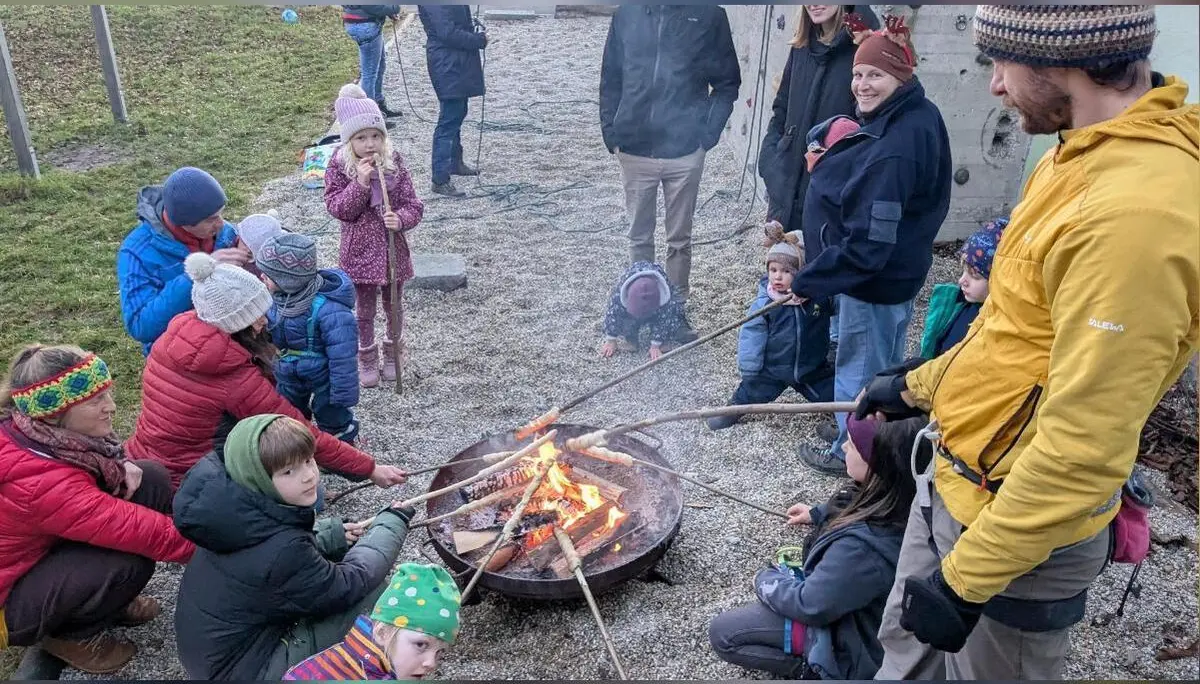 Kinder und Erwachsene rösten Stockbrot an der Feuerschale; Winterkleidung, lockere Gruppe und Kiesplatz im Freien. | © DAV Markt Schwaben · Familiengruppe