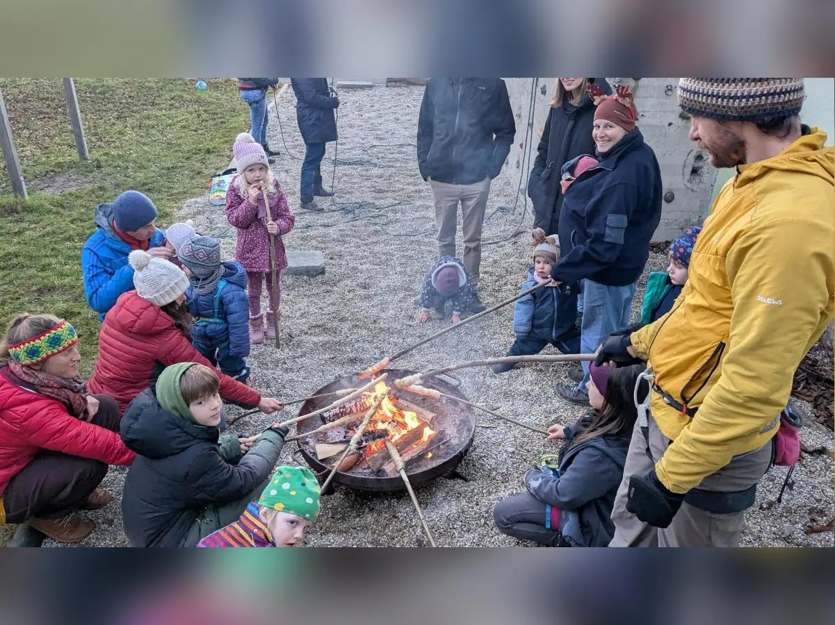 Kinder und Erwachsene rösten Stockbrot an der Feuerschale; Winterkleidung, lockere Gruppe und Kiesplatz im Freien. | © DAV Markt Schwaben · Familiengruppe