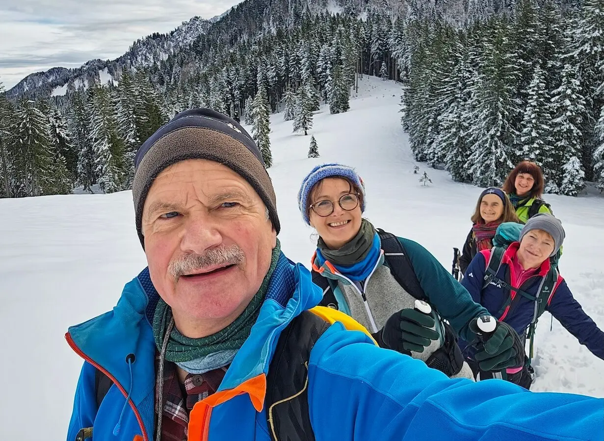 Fünf Wandernde posieren für ein Selfie im Schnee; im Hintergrund verschneite Tannen und Berge unter blauem Himmel. | © DAV Markt Schwaben | Foto: Lutz Gründel
