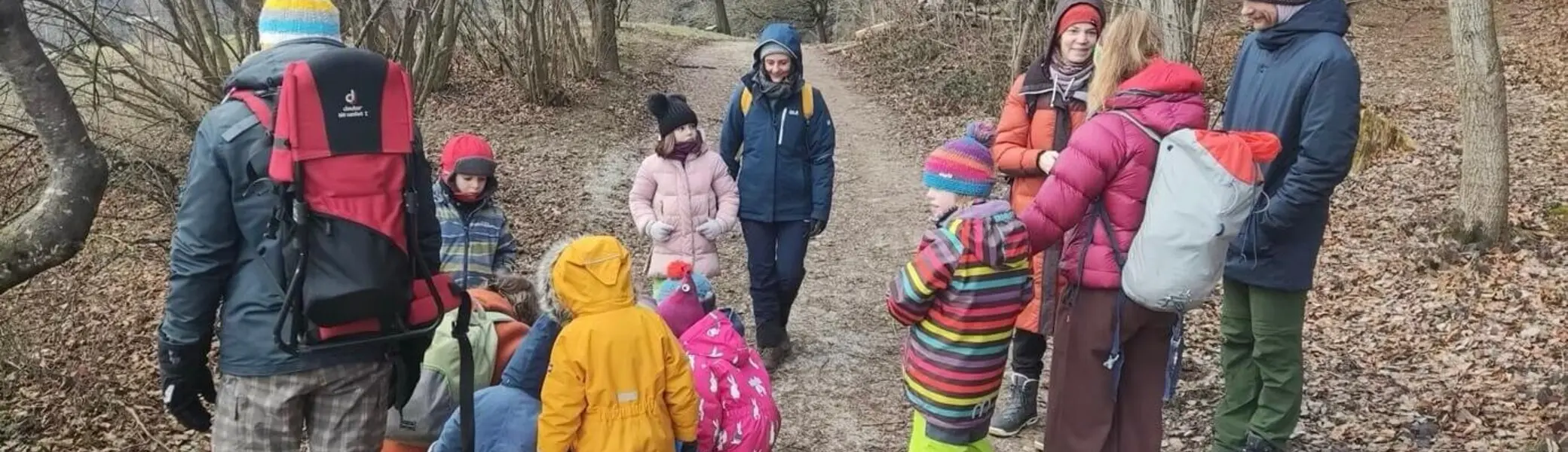 Gruppe von Erwachsenen und Kindern in bunter Winterkleidung auf einem Waldweg bei einem Naturausflug. | © DAV Markt Schwaben Familiengruppe