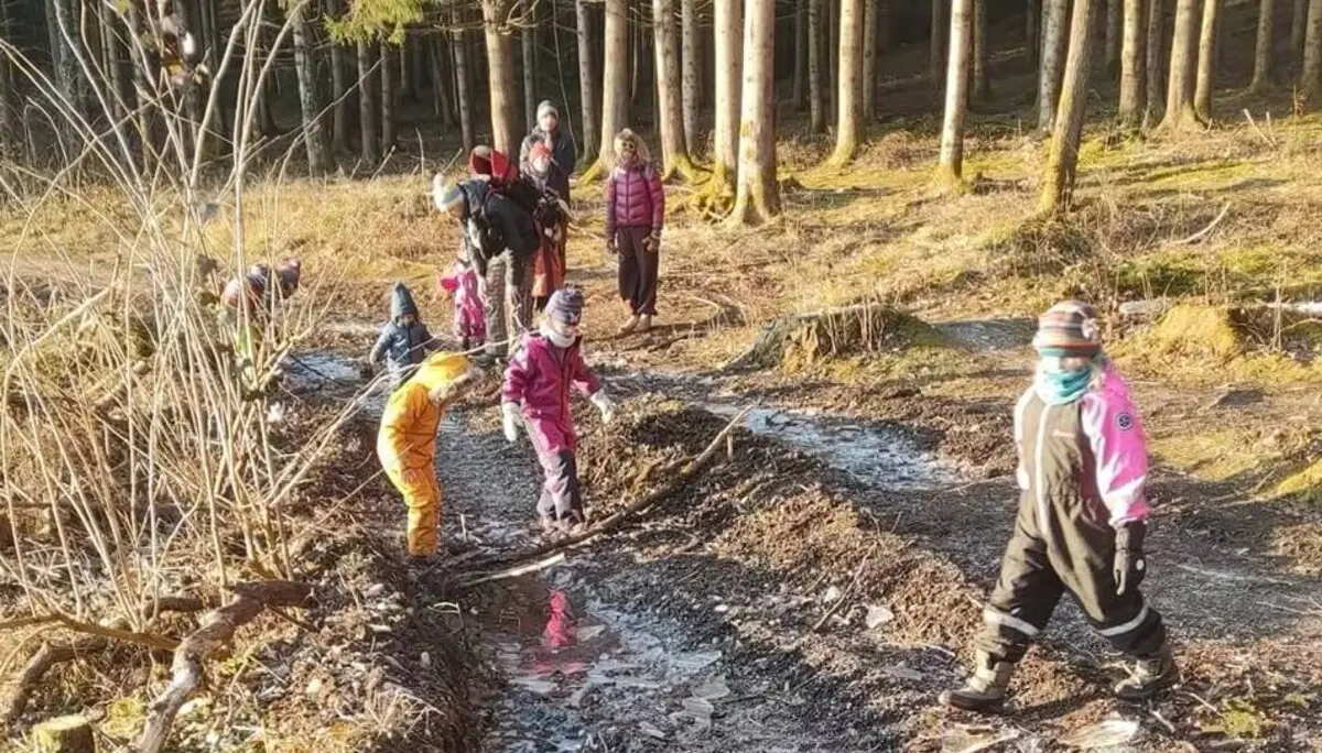 Kinder und Erwachsene spielen auf einem matschigen Waldweg mit Pfützen, umgeben von kahlen Bäumen. | © DAV Markt Schwaben Familiengruppe