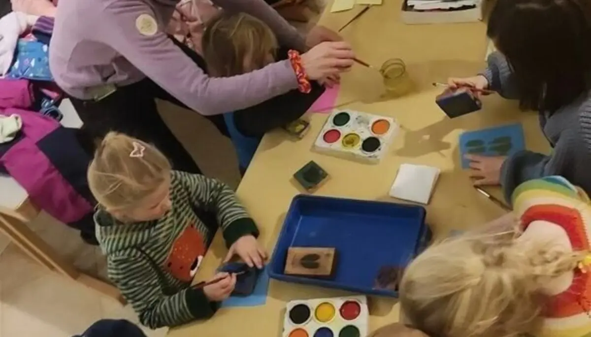 Gruppe von Kindern und Erwachsenen bei einer kreativen Bastelaktivität an einem Tisch mit Bastelmaterialien. | © DAV Markt Schwaben Familiengruppe