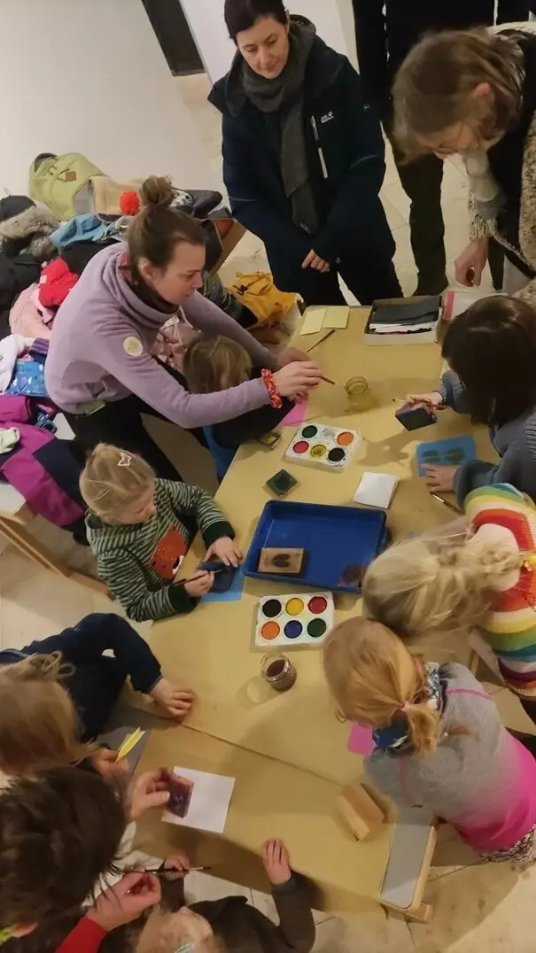 Gruppe von Kindern und Erwachsenen bei einer kreativen Bastelaktivität an einem Tisch mit Bastelmaterialien. | © DAV Markt Schwaben Familiengruppe