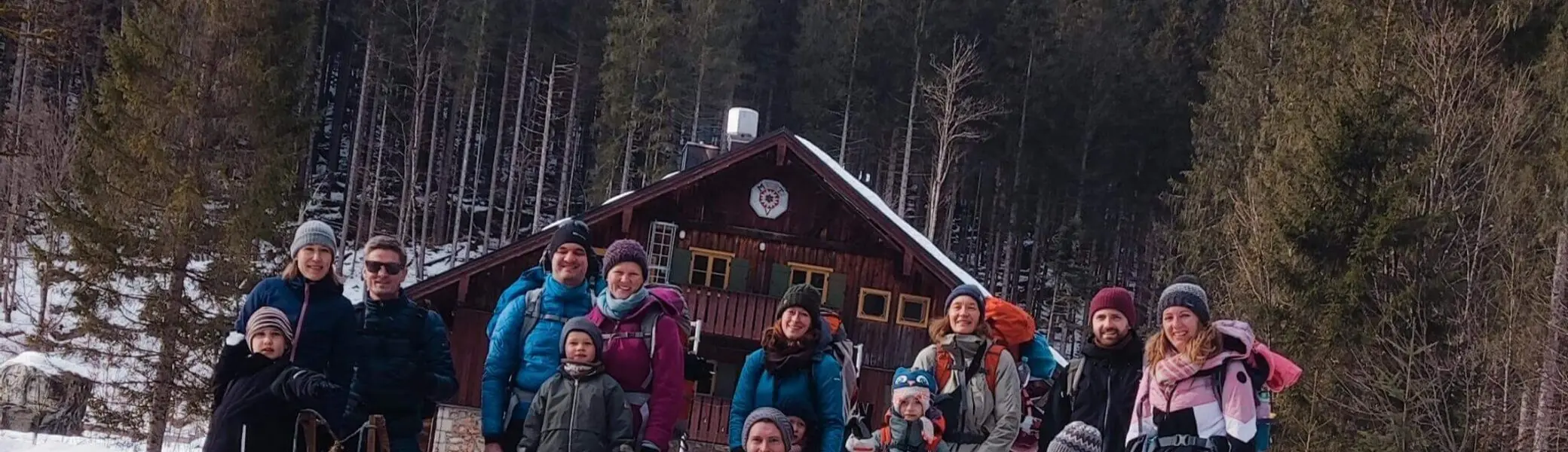 Gruppe aus Kindern und Erwachsenen posiert fröhlich vor dem Blecksteinhaus am Spitzingsee in winterlicher Schneelandschaft. | © DAV Markt Schwaben