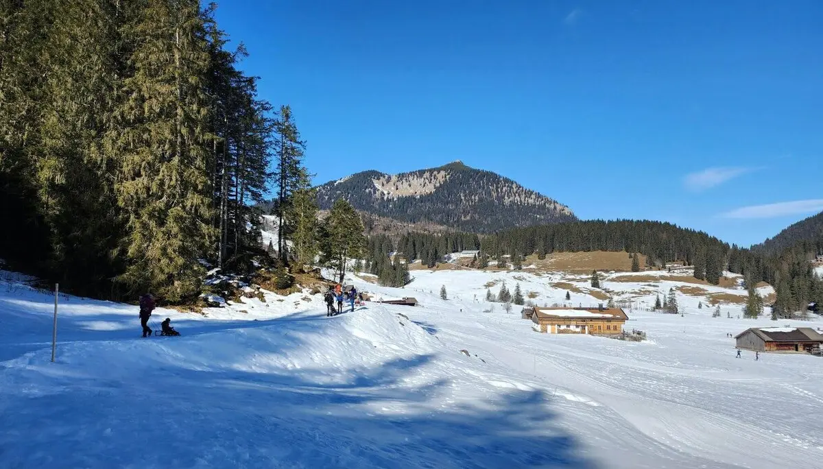 Sonnige Winterlandschaft mit Spaziergängern, einige ziehen Schlitten mit Kindern. | © DAV Markt Schwaben