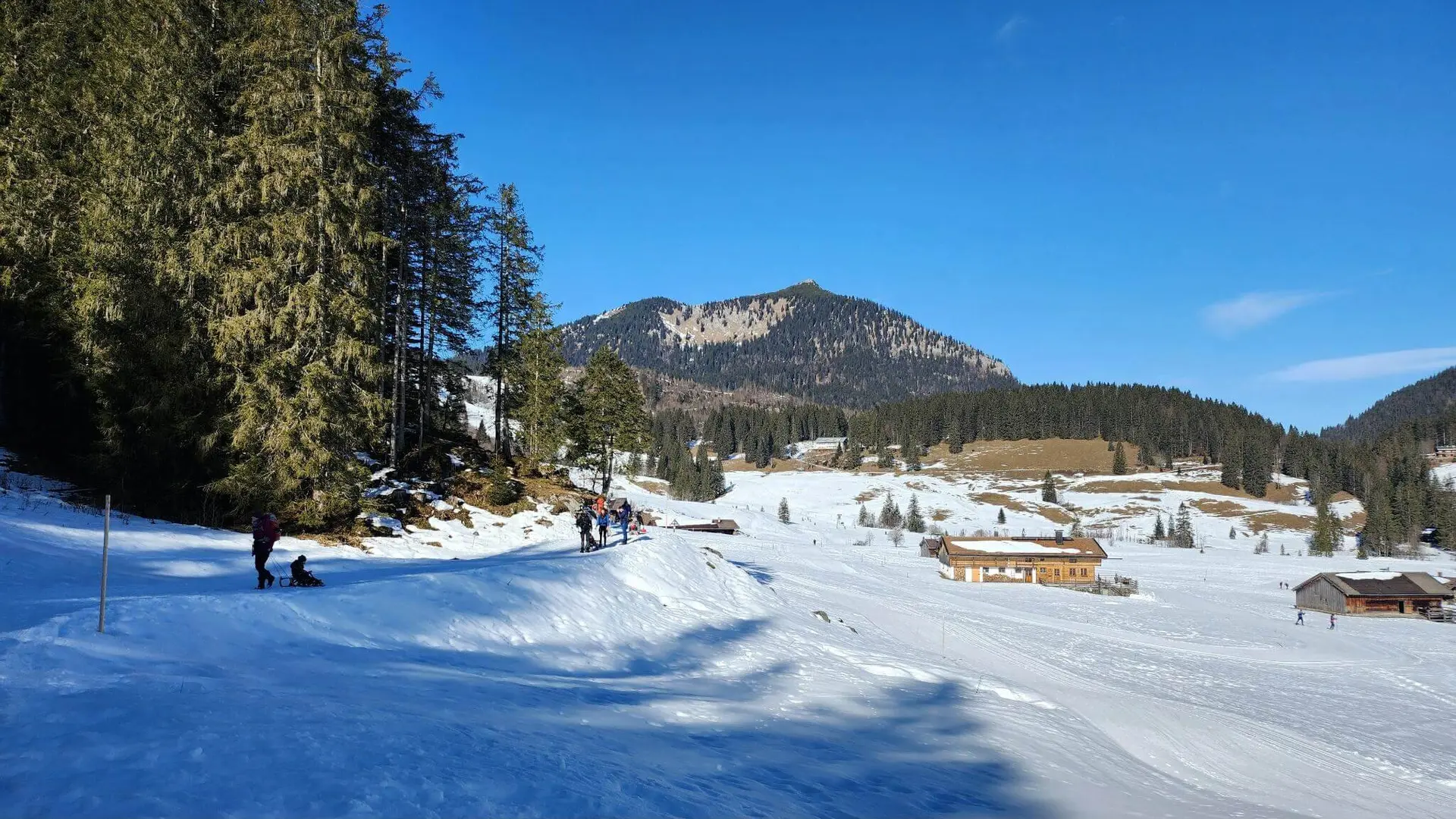 Sonnige Winterlandschaft mit Spaziergängern, einige ziehen Schlitten mit Kindern. | © DAV Markt Schwaben