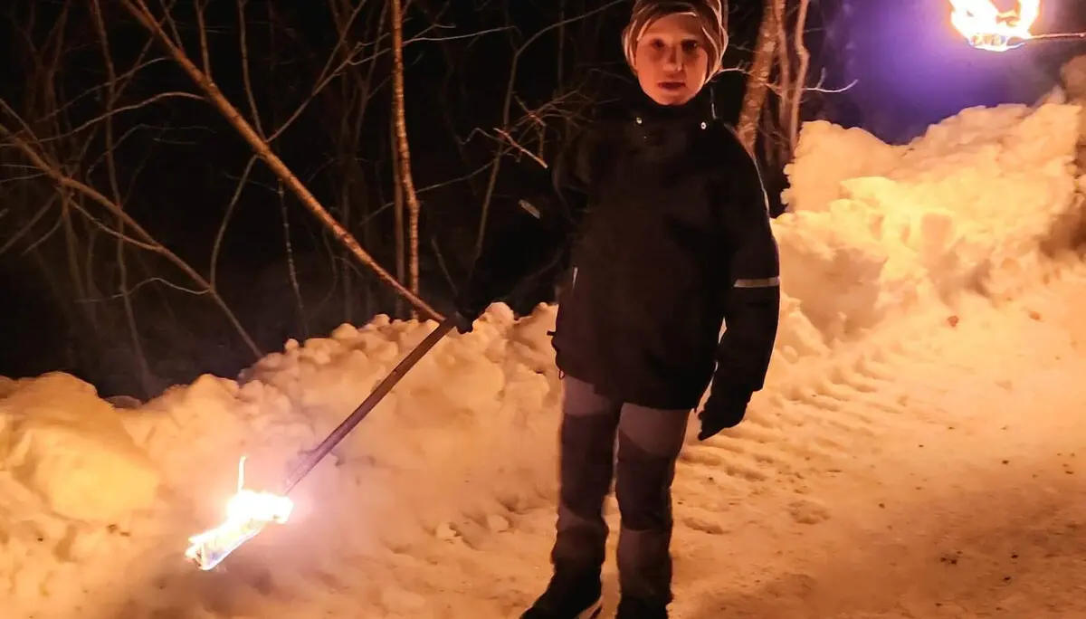 Ein Kind in der dunklen Nacht, warm angezogen, hält eine brennende Fackel. | © DAV Markt Schwaben