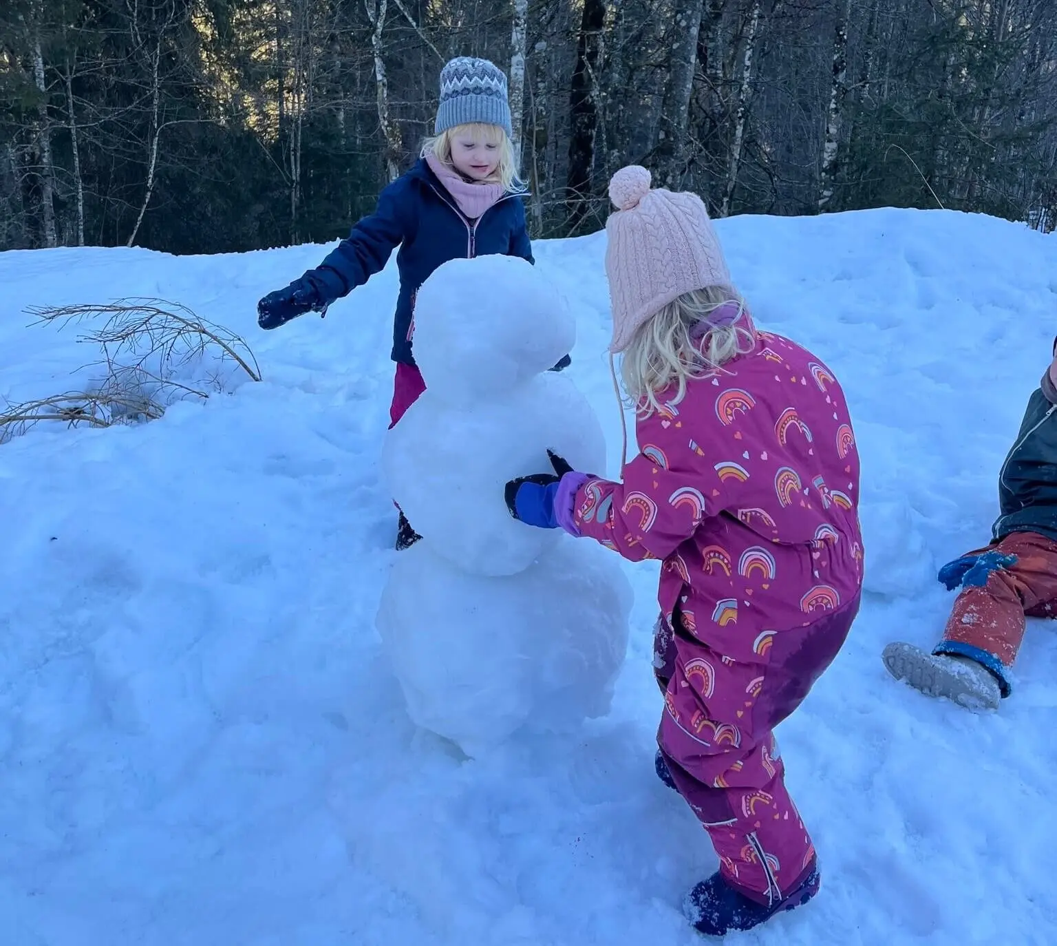 Zwei Mädchen bauen einen Schneemann. Sie sind warm angezogen und konzentriert bei der Arbeit. | © DAV Markt Schwaben