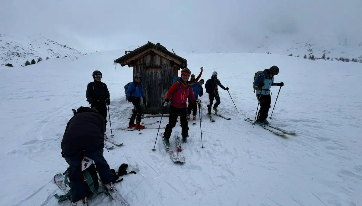 Skitourengruppe bereitet sich vor der kleinen Holzhütte auf die Abfahrt vor; eine Person beim Abfellen im Vordergrund. | © DAV Markt Schwaben · Foto: Markus Sellmeier