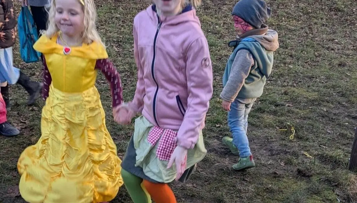 Drei lächelnde Kinder in bunten und verspielten Outfits draußen auf einer Wiese. | © DAV Markt Schwaben