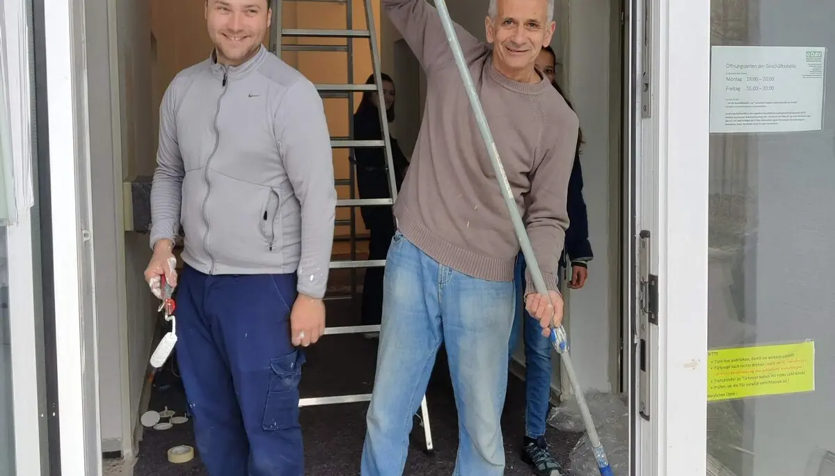 Zwei gut gelaunte Mitglieder streichen Heizkörper und Wände im Innenbereich während des Arbeitsdienstes. | © DAV Markt Schwaben