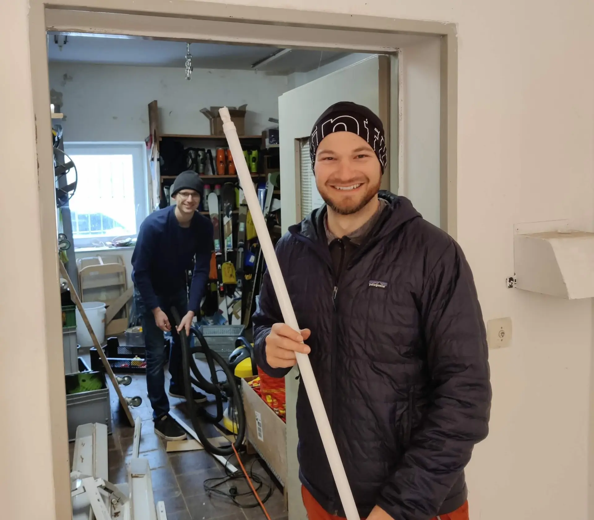 Zwei Personen im Materiallager, die Person im Vordergrund hält eine Leuchtstoffröhre, beide lächeln. | © DAV Markt Schwaben