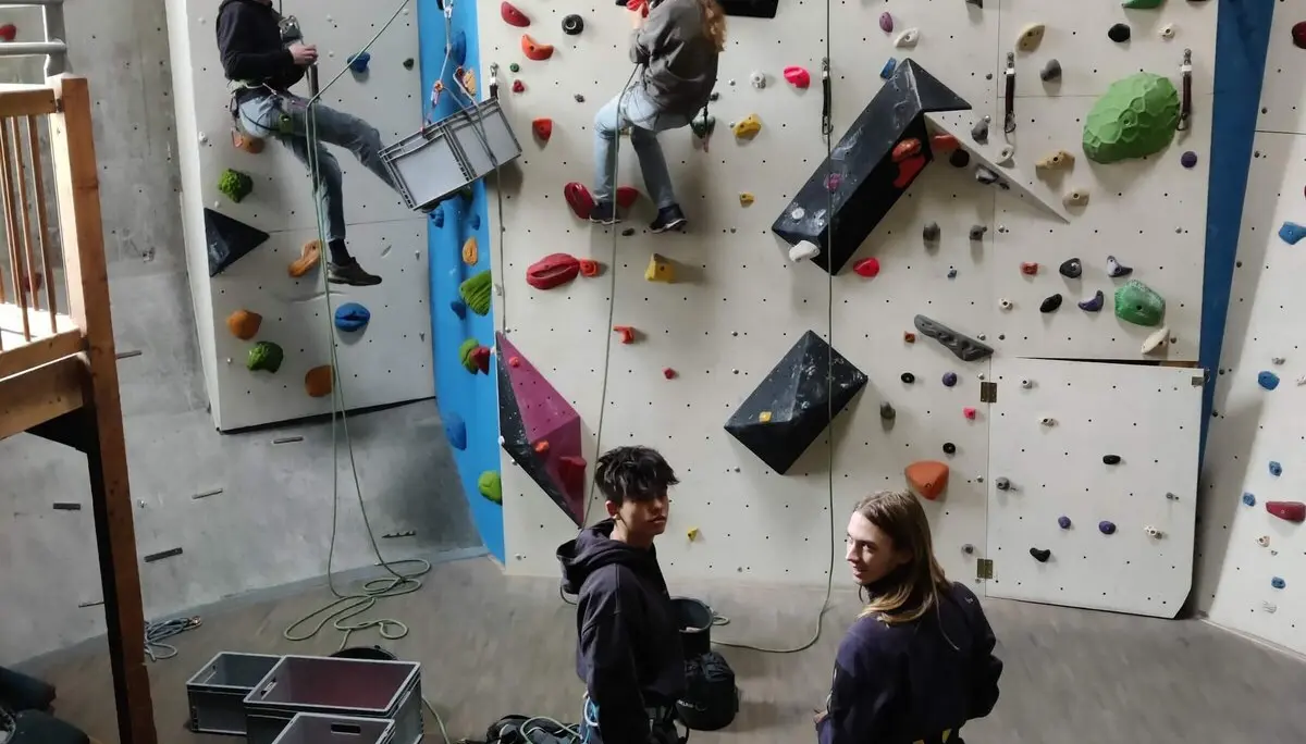 Vier Personen in einer Indoor-Kletterhalle, zwei klettern gesichert, zwei beobachten mit Kletterausrüstung | © DAV Markt Schwaben