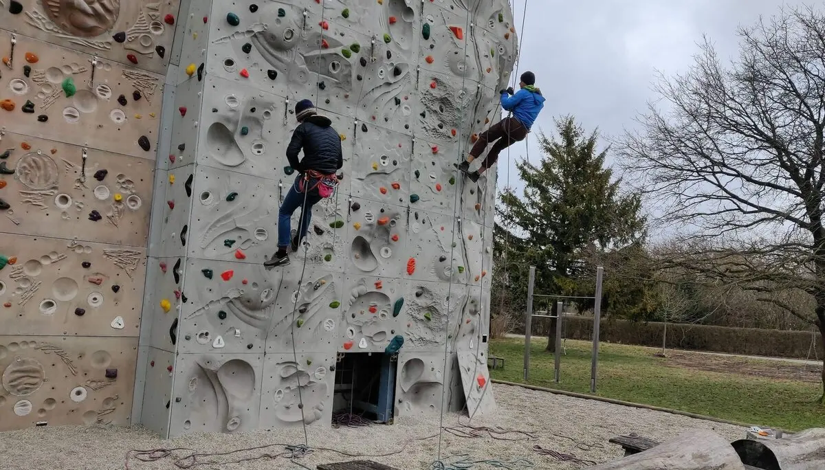 Zwei Personen klettern gesichert an einer bunten Outdoor-Kletterwand. | © DAV Markt Schwaben