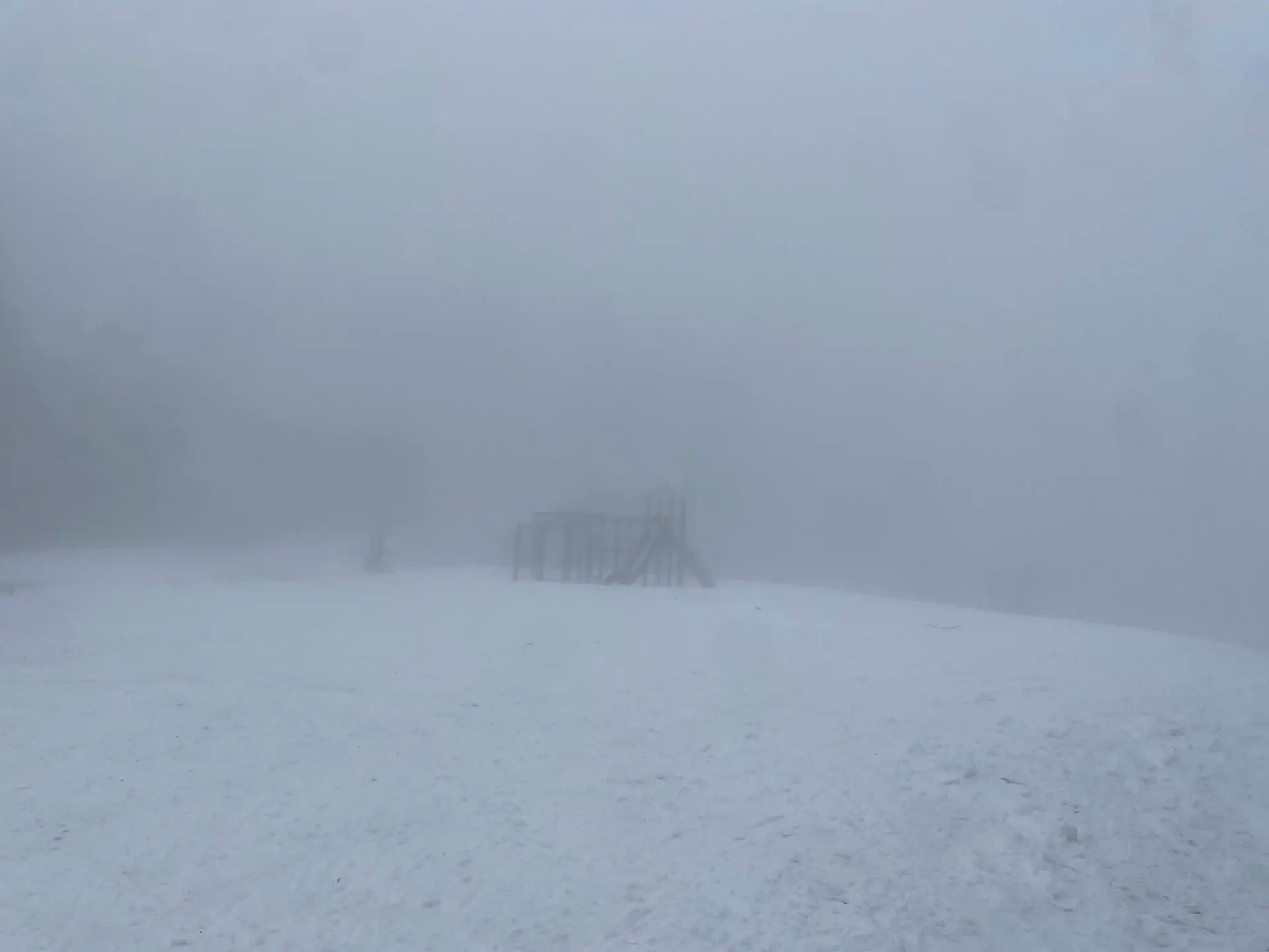 Spielplatzstruktur mit Rutsche und Kletterelementen, umgeben von Schnee und dichtem Nebel für eine mystische Atmosphäre. | © DAV Markt Schwaben