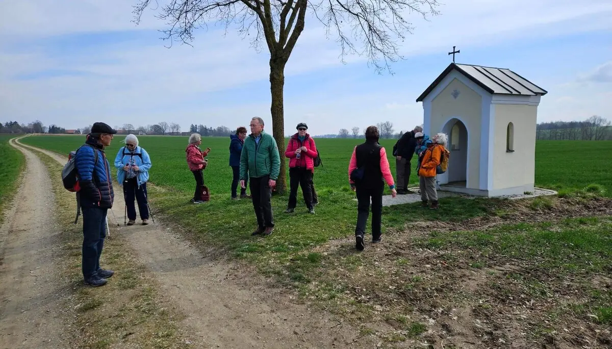 eniorengruppe auf einem sonnigen Feldweg, lachend und entspannt beim Wandern – neben einer kleinen Kapelle | © DAV Markt Schwaben