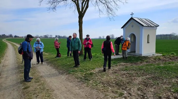 eniorengruppe auf einem sonnigen Feldweg, lachend und entspannt beim Wandern – neben einer kleinen Kapelle | © DAV Markt Schwaben