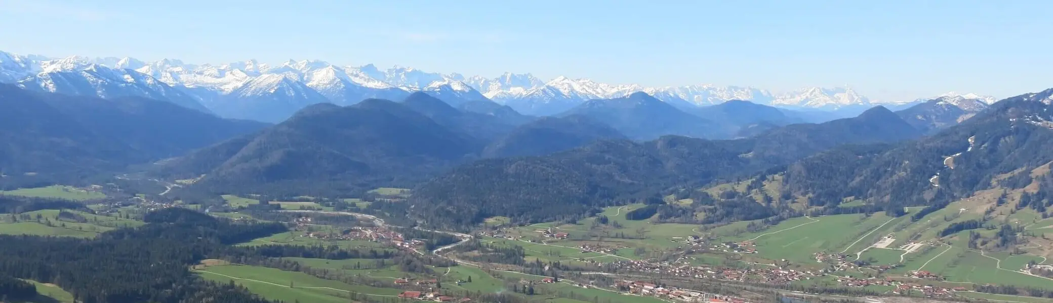Panoramablick auf ein grünes Tal mit kleinen Dörfern, umgeben von majestätischen, schneebedeckten Bergen unter klarem Himmel – eine malerische und beruhigende Landschaft. | © DAV Markt Schwaben | Foto Erwin Matzinger
