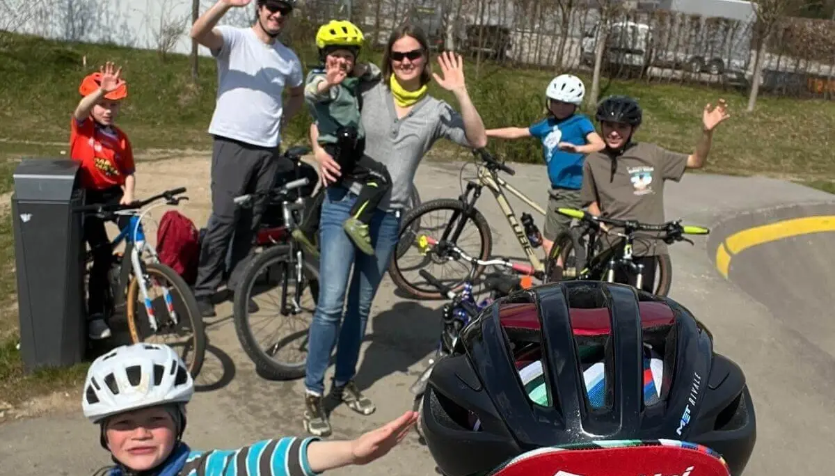Kinder und Erwachsene trainieren auf dem Pumptrack, tragen Helme und winken fröhlich – Sicherheit & Teamgeist. | © DAV Markt Schwaben | Foto Miron Thoms