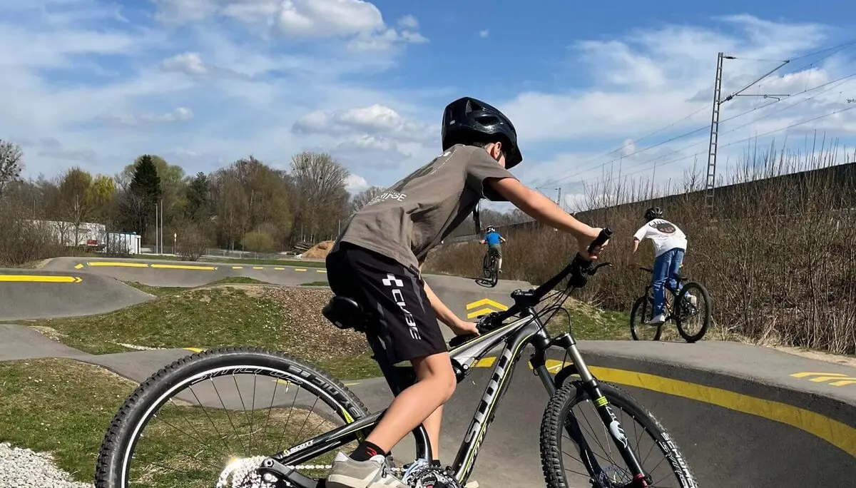 Biker auf BMX-Track mit Helm, meistern Kurven und Sprünge bei klarem Himmel – Action und Fahrspaß pur! | © DAV Markt Schwaben | Foto Miron Thoms