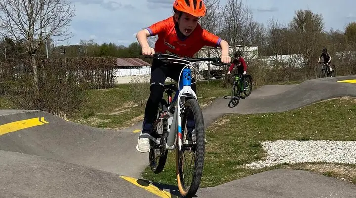 Person in orangem Helm und Shirt springt mit Fahrrad über BMX-Rampe – Action und Techniktraining pur! | © DAV Markt Schwaben | Foto Miron Thoms